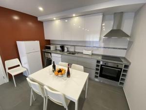 a kitchen with a white table and white appliances at Da Silva Surf Lodge Three in Lourinhã