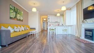 ブラショヴにあるCentral Maximus Apartmentのリビングルーム(黄色のソファ付)、キッチンが備わります。