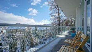 ブラショヴにあるCentral Maximus Apartmentの雪に覆われた木々と椅子2脚付きのバルコニー