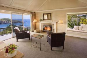 a living room with a fireplace and a view of the ocean at SCP Mendocino Coast Lodge in Albion