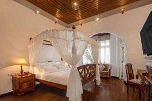 1 dormitorio con 1 cama blanca con dosel en The Clovelly Bungalow, en Nuwara Eliya