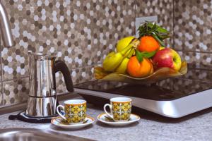 un bol de fruta en una barra de cocina con dos tazas en Cico Art Suite, en Nápoles 31 fotos más