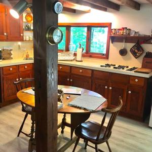 eine Küche mit einem Holztisch und einer Uhr in der Unterkunft Quiet cottage on wooded property in Lusby