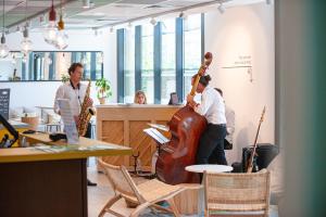 un grupo de personas tocando instrumentos en una habitación con una guitarra en Apparthotel Le Hüb TOULON en Toulon