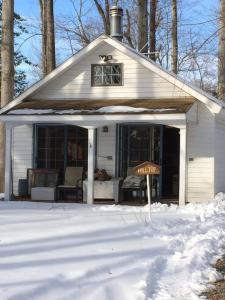 ein weißes Haus mit einem Schild im Schnee in der Unterkunft Quiet cottage on wooded property in Lusby