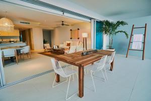 a dining room with a wooden table and white chairs at Luxury 3bdr Beachfront Condo, Peninsula Ixtapa in Ixtapa