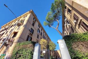 wysoki budynek z drzewem obok niego w obiekcie Gazometro Apartment SelfCheck-in w Rzymie