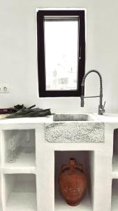 a kitchen sink with a vase sitting under a mirror at Sol living in Tinos +39 photos