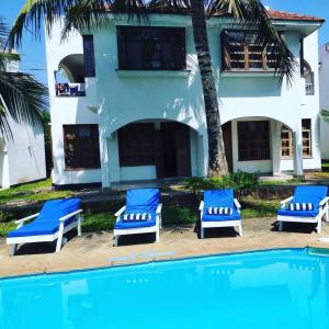 a group of blue lounge chairs next to a house at Diani Breeze Villas in Diani Beach