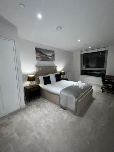 a bedroom with a large bed and a flat screen tv at Stylish Apartment Docklands in London