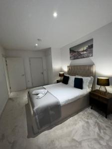 a bedroom with a large white bed with two lamps at Stylish Apartment Docklands in London