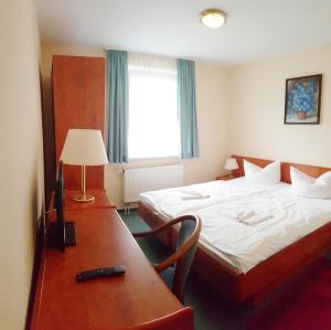 une chambre d'hôtel avec un lit et un bureau avec une lampe dans l'établissement Pension Mesogios, à Bad Doberan