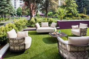 un patio con sillas blancas, mesa y césped en Hotel Da Vinci, en Milán