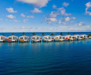 une rangée de cottages sur un quai dans l'eau dans l'établissement Oaga Art Resort Maldives - Greatest All Inclusive, à Atoll Malé Nord