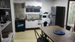 uma pequena cozinha com uma mesa e um frigorífico em Hermoso amplio casa container Balneario Buenos Aires em Balneario Buenos Aires