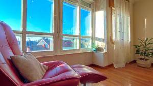una sala de estar con una silla roja y ventanas en Duplex acogedor CAMINO INGLÉS a 10 min de Santiago en Sigüeiro