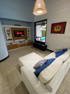 嘎林海斯港的住宿－Casa Familiar 5 Suítes Porto de Galinhas，客厅配有白色沙发和电视