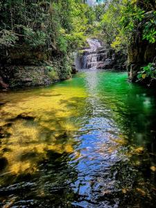 einem Bach mit grünem Wasser und einem Wasserfall in der Unterkunft Casa Temporada Espaço Vip in Barra do Garças