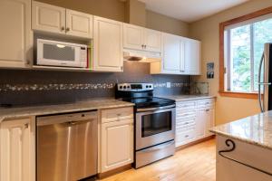 a kitchen with white cabinets and a stove and microwave at Polar Peak by Fernie Central Reservations in Fernie