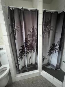 a bathroom with a shower curtain with palm trees at Arsi Hostel in Hamburg