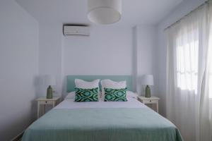 Dormitorio blanco con cama con almohadas verdes en GINVA - Villa Puerto Sherry, en El Puerto de Santa María