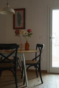 una mesa de comedor con 2 sillas y un jarrón con flores en CasaMancio, loft in heart of medieval Tuscan city, en Pistoia