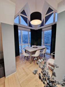a dining room with a table and chairs and windows at Apartament Gwiazda 503 in Krynica Zdrój