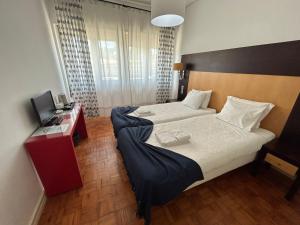 a hotel room with two beds and a television at Discovery Apartment Benfica in Lisbon