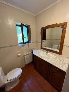 bagno con servizi igienici, lavandino e specchio di Casa Musoles a Comillas