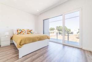 ein Schlafzimmer mit einem Bett und einem großen Fenster in der Unterkunft Villa Beija Flor in Charneca + 24 Fotos