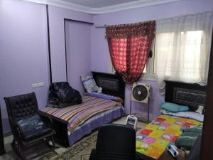 a bedroom with two beds and a chair and a window at Duck Nest (Kak Kak) in Cairo
