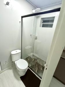 a bathroom with a toilet and a glass shower at Loft Lux 4 in Chapecó