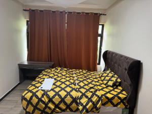 a bedroom with a bed with a yellow and black comforter at Steady State Apartment 1 in Lusaka