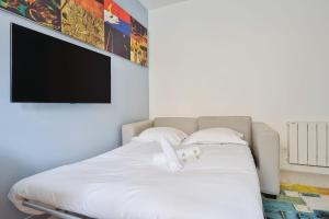 1 cama con sábanas blancas y TV de pantalla plana. en Nice studio with garden near Paris in Vanves - Welkeys en Vanves