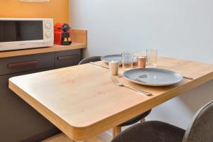 a wooden table with two plates and a microwave at Nice studio with garden near Paris in Vanves - Welkeys in Vanves