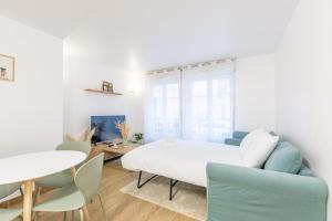 a white bedroom with a bed and a table and chairs at L'Emeraude by Plaza - Proche Disneyland Paris in Chessy