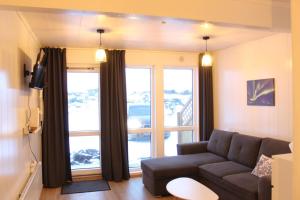 a living room with a couch and a large window at Cozy mini house close to newest volcano and the ocean in Vogar