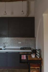 a kitchen with black cabinets and a stove and a table at CasaMancio, loft in heart of medieval Tuscan city in Pistoia