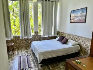 a bedroom with a bed in a room with windows at Deck da Villa Picinguaba in Ubatuba