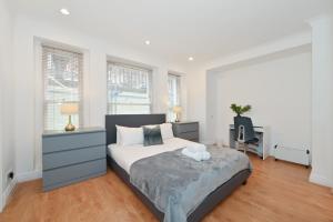 a bedroom with a bed and a desk and windows at London Choice Apartments - Gloucester Road - Kensington in London