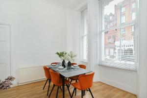 a dining room with a table and orange chairs at London Choice Apartments - Gloucester Road - Kensington in London