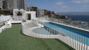 a swimming pool with a white fence next to a building at Resetéate frente al Mar!! Disfruta en primera línea de Cochoa-Reñaca in Viña del Mar