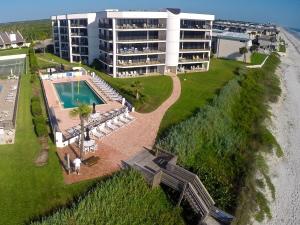 an aerial view of a resort with a pool and a building at Ground floor beachfront with steps to the beach and pool & beach access in New Smyrna Beach