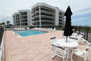 a patio with a table and chairs next to a pool at Ground floor beachfront with steps to the beach and pool & beach access in New Smyrna Beach