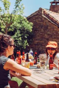 Deux femmes assises sur une table de pique-nique avec des bouteilles de bière dans l'établissement Casa Rural Ger, 
