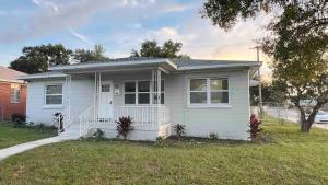 a small white house on a grass field at Our Nest - Historic Ybor City in Tampa