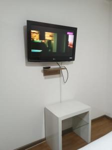 einen TV an einer Wand mit einem weißen Tisch in der Unterkunft Suites+Arte in Quito