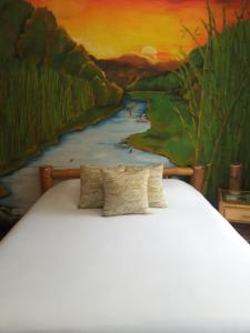 un lit devant une peinture de rivière dans l'établissement Suites+Arte, à Quito