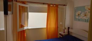 a bedroom with an orange curtain and a window at Tritones Playa in Pinamar