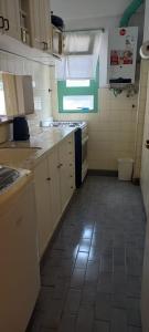 a small kitchen with white cabinets and a tile floor at Tritones Playa in Pinamar